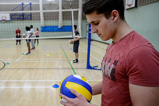 A young man gets his mind into the zone as he prepares to serve in a game of softball on court in the sports hall