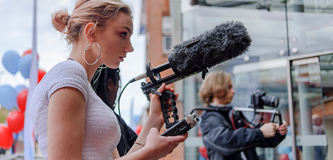 A young woman with sound recording equipment on a documentary making assignment